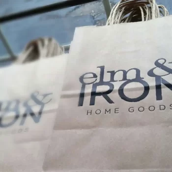 Close up photo of Elm & Iron Home Goods logo printed on brown paper bags